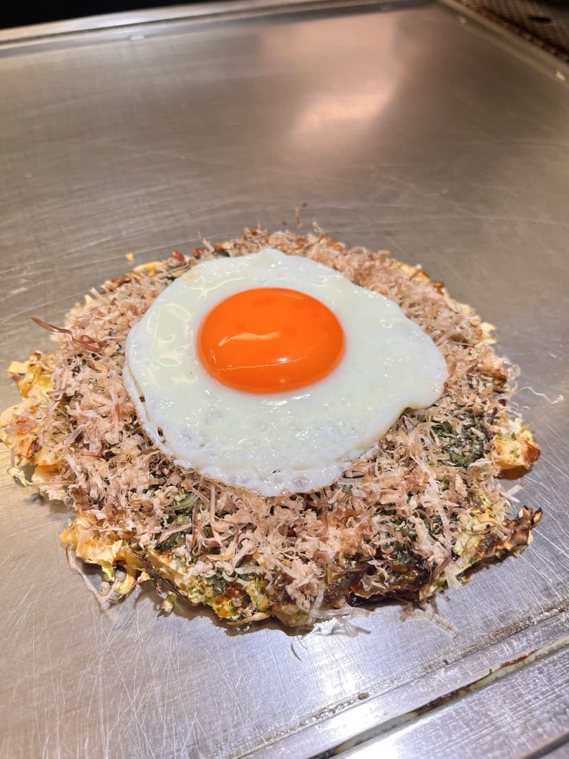 The okonomiyaki on the griddle in front of us