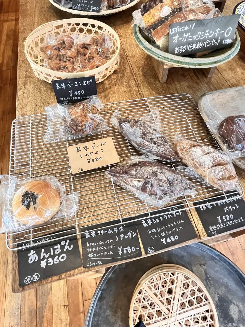 The bread shelves with handwritten price cards: anpan, the cream cheese bun, and brown-rice baguettes
