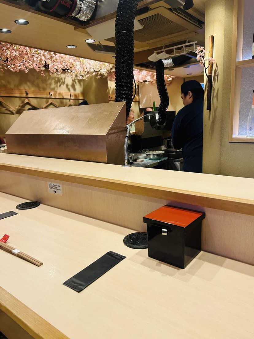 The counter seats, with cherry blossoms overhead and the fryer in front of you